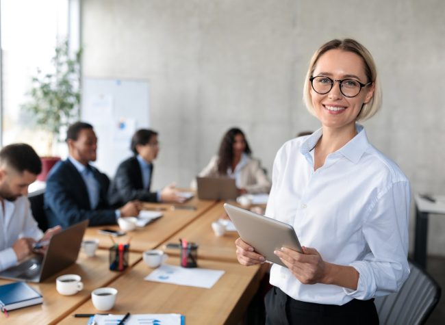 Successful Businesswoman Holding Digital Tablet Standing In Modern Office